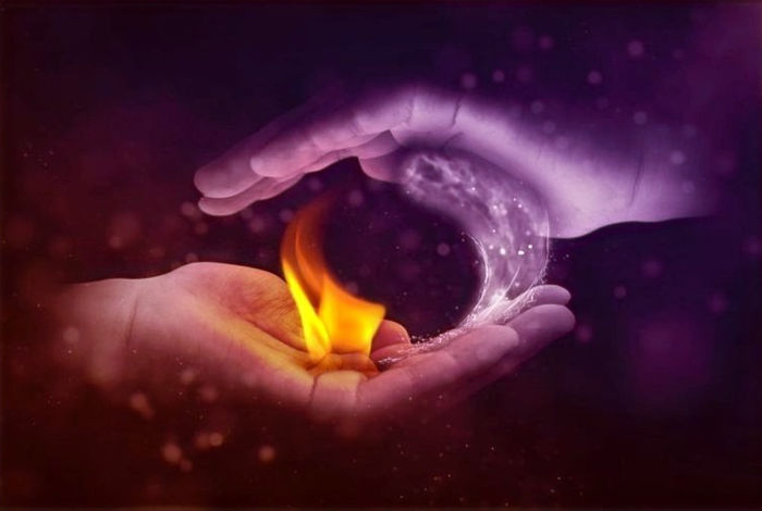 Mains tenant une flamme sur fond sombre