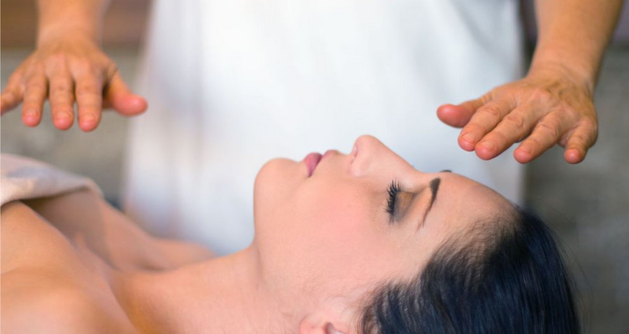 Mains d'un magnétiseur au-dessus du visage d'une personne allongée