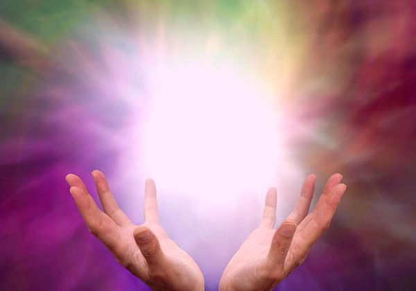 Mains ouvertes entourées d'un halo lumineux, image du soin énergétique